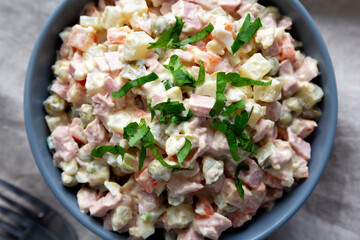 Homemade Olivier salad in a Bowl on a white wooden background, top view. Flat lay, overhead, from above.