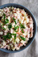 Homemade Olivier salad in a Bowl on a white wooden background, top view. Flat lay, overhead, from above.