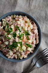 Homemade Olivier salad in a Bowl on a white wooden background, top view. Flat lay, overhead, from above. Space for text.