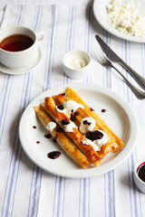 Fried Stuffed Pancakes Blintzes. Russian thin pancakes with cottage cheese, sour cream and jam. Healthy traditional breakfast.Tasty stuffed pancakes crepes with fillings. Kid's menu.