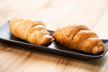 Two croissants are on plate. Croissant is a buttery, flaky, French  pastry. This bread uses the French yeast-leavened laminated dough. Crispy and yummy.