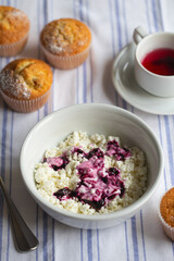 Homemade cottage cheese in a deep plate. Milk product. Granular cottage cheese with black currant jam