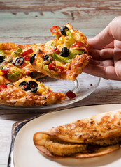 close up of pizza with a hand picking it up