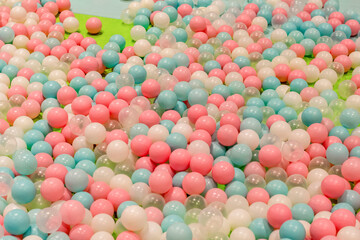 Smal plastic balls for indoor ball pit children kids playground. White blue pink colored background