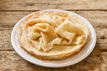 Pancakes (bliny) in a plate on a wooden background.