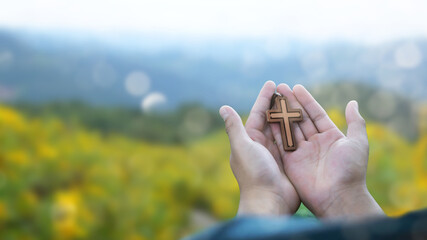 man praying with cross in nature sunrise background, Symbol of Faith.