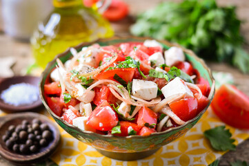 Salad with tomatoes, onions and mozzarella, garnished with herbs. Wooden background.