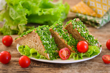 Appetizing sandwich with herbs and tomatoes. Wooden background.