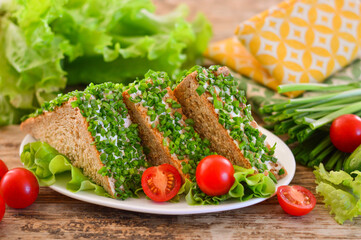 Appetizing sandwich with herbs and tomatoes. Wooden background.