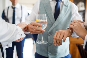 The groomsmen help fasten the groom's cufflinks