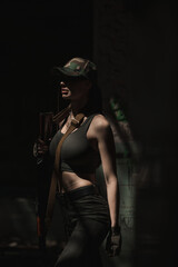Fototapeta na wymiar A Ukrainian military girl stands with an AK-74 assault rifle inside a destroyed building
