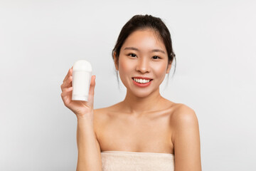 Young Asian woman showing deodorant in bathroom