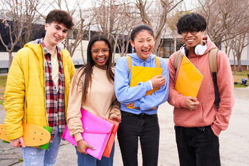 Confident multiracial group of students holding books and smiling at camera, campus university on background, learning and education concept. Smiling happy young people having fun together