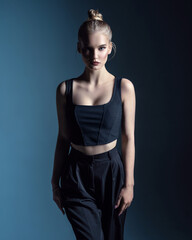 A beautiful delicate girl in a top with beautiful hair. Grey background. Hair cosmetics. Cosmetics advertising. Natural makeup.