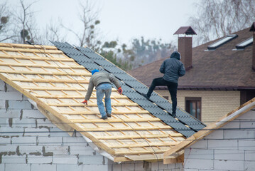 a professional roofer with electric screwdriver covers repairs the roof