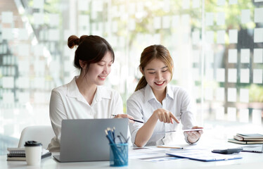 Two Young Asian businesswoman discuss with new startup project Idea presentation, analyze planning and financial statistics and investment market at office.