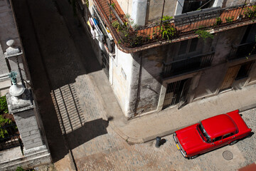 Top-down view of a small city street with historical buildings and a parked red retro car.