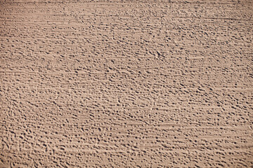 Horizontal panoramic photo of a sandy beach with lots of footprints