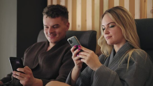 visitors of recreation complex, man and woman are resting after health treatments in spa center, using mobile phones