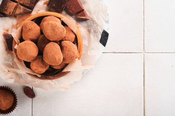 Chocolate truffles with cocoa powder in wooden dish on old cracked tile table background. Tasty sweet chocolate truffles candies. Valentine's Day and Mother's Day concept with copy space. Top view.