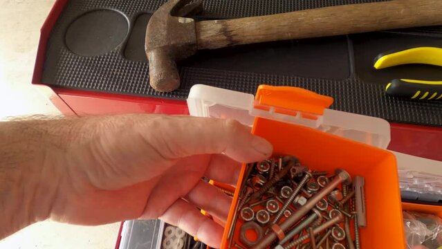 Searching through a toolbox for random screws. Close up.