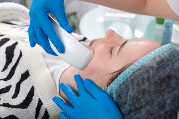 Young woman receiving electric galvanic anti-aging face spa massage at beauty salon.