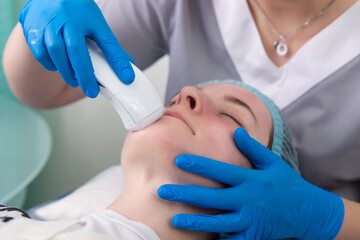 Naklejka premium Young woman receiving electric galvanic anti-aging face spa massage at beauty salon.