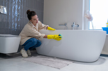 A woman doing cleaning at home and disinfecting the bathroom