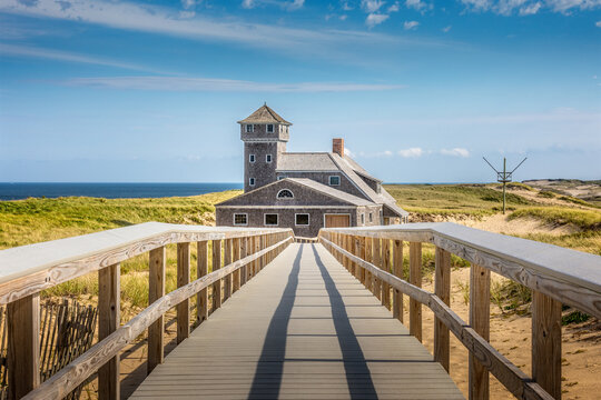 Blue sky and dunes with grass in front of the life saving station building in Provincetown