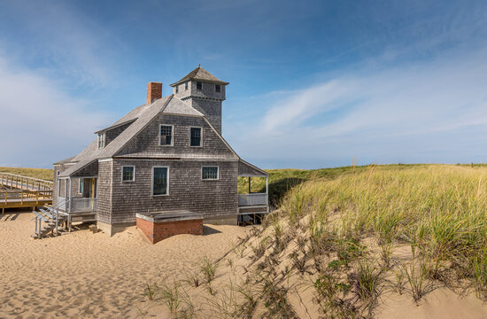 Blue sky and dunes with grass in front of the life saving station building in Provincetown