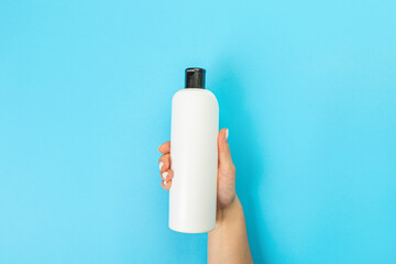 Housewife's hand holds a spray with cleaning agent on a blue background. Detergent for various surfaces in the kitchen, bathroom and other rooms. Close-up. Light pastel blue background. place for text
