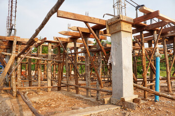Fototapeta na wymiar Temporary poles and wooden scaffolding support the concrete beam framework at the house construction site.