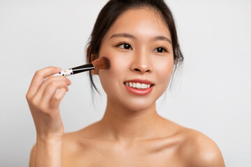 Fototapeta premium Portrait of beautiful Asian woman with makeup brush