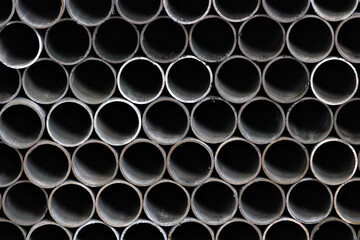 Maetallic pipes of the same diameter are neatly stacked. View of pipes from the front. Background...