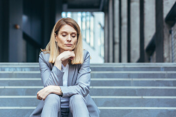 Close-up portrait of sad upset business woman sitting tired on stairs of office building