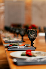 in a loft-style restaurant there is a long table served with glasses, plates with warm lighting and paintings
