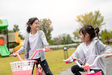 Obraz premium happy cheerful child girl riding a bike in Park in the nature