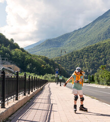 happy young woman in protective equipment riding on roller skates along embankment in summer active...