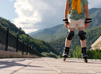 woman in protective equipment riding on roller skates along embankment in summer active lifestyle,...