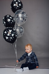 Little boy on a gray background with balloons. little gentleman and his first birthday