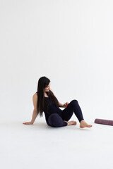 Fototapeta na wymiar Young beautiful woman practicing yoga on a white background. Young beautiful girl doing exercises at home. Harmony, balance, meditation, relaxation, healthy lifestyle concept 
