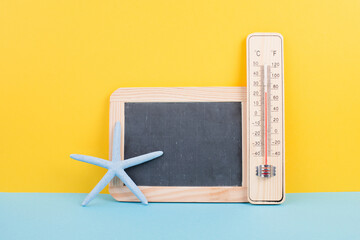 Empty chalkboard with a thermometer and an sea star, holiday background, summer vacation, hot weather, environmental issue