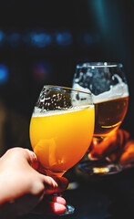 two glass of beer in man hand. Beer glasses clinking in bar or pub