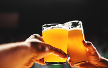 two glass of beer in man hand. Beer glasses clinking in bar or pub