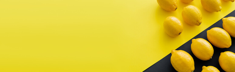 Flat lay with organic lemons on yellow and black surface, banner