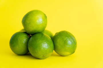 Fresh green limes on yellow surface