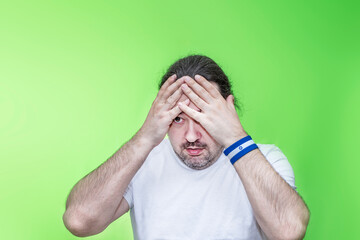 An adult, unshaven man in desperation holds his head. Bracelet in the colors of the Israel flag.