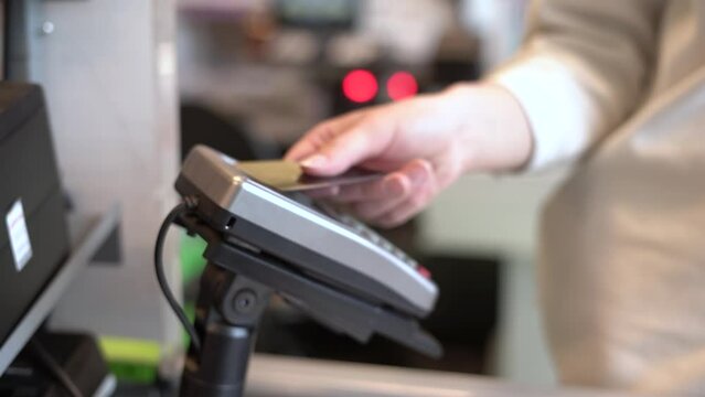 Woman's hand, payment by bank card at the terminal at the cash register in the supermarket