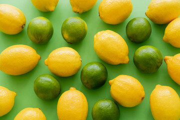 Flat lay of lemons and limes on green background