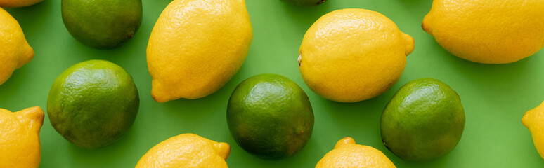 Top view of juicy lemons and limes on green background, banner